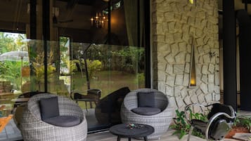 A modern outdoor seating area with wicker furniture and a stone wall.