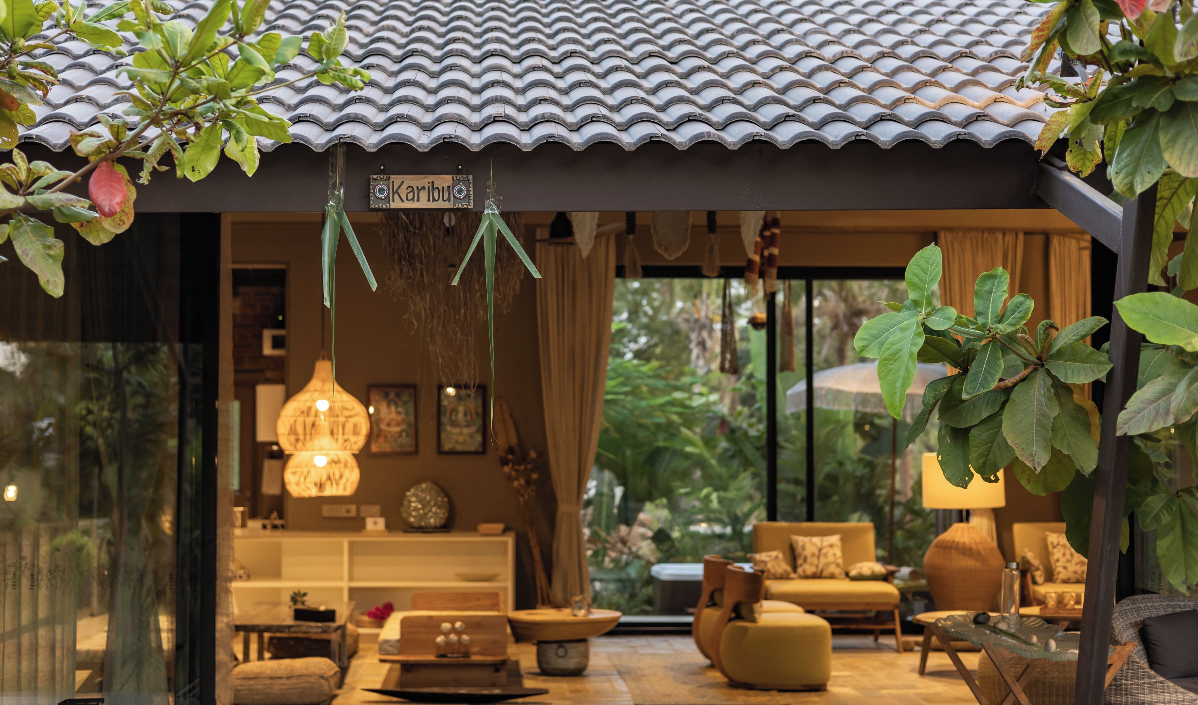A traditional Japanese-style interior with a tiled roof, a sign reading 'Karibu', and a cozy seating area with cushions and a hanging light fixture.