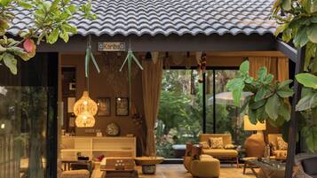 A traditional Japanese-style interior with a tiled roof, a sign reading 'Karibu', and a cozy seating area with cushions and a hanging light fixture.