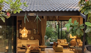 A traditional Japanese-style interior with a tiled roof, a sign reading 'Karibu', and a cozy seating area with cushions and a hanging light fixture. - ELIVAAS Prive Sravasti Forest View (Bengaluru)