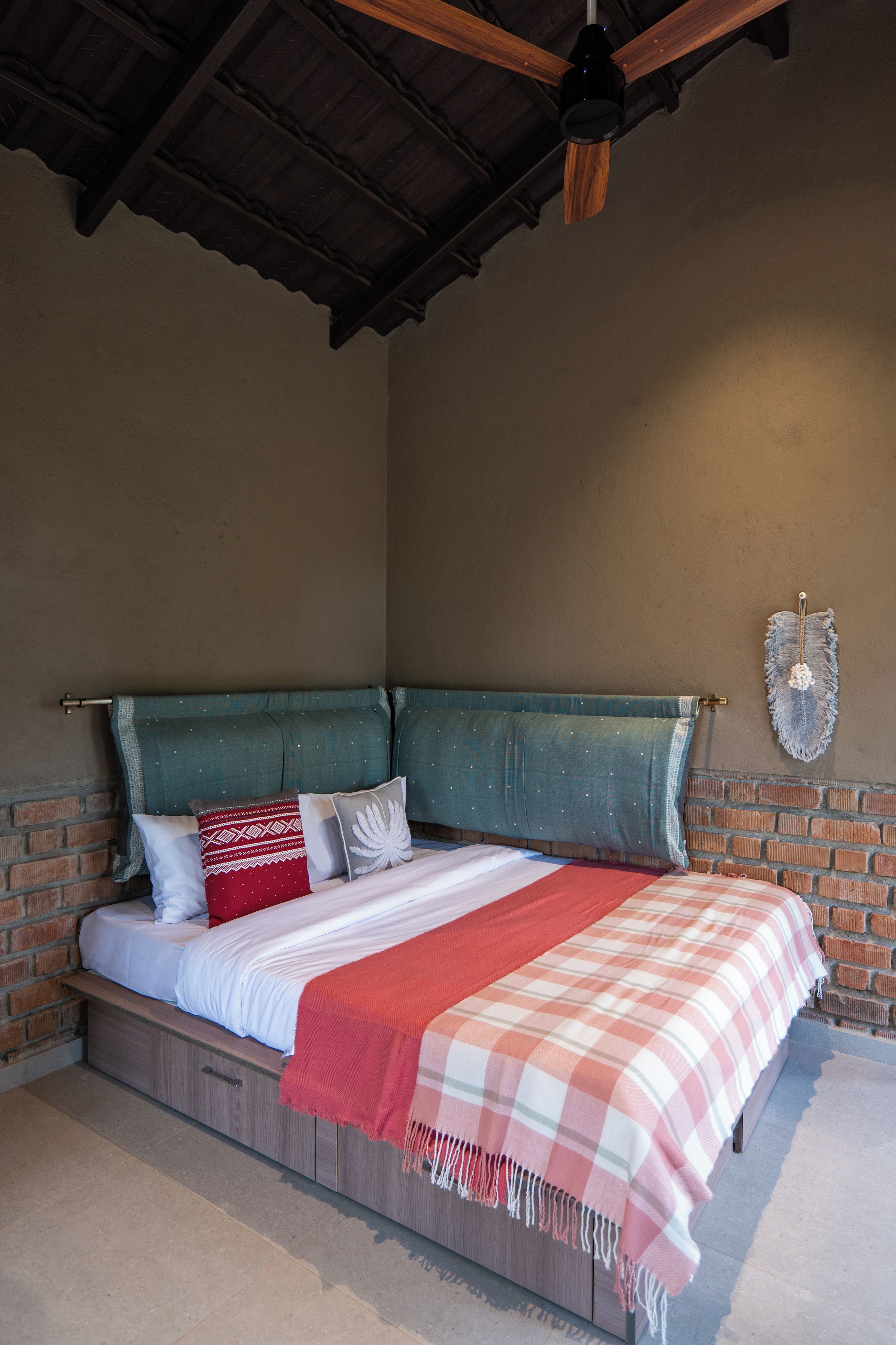 A bedroom with a bed, a wooden headboard, a brick wall, and a ceiling fan.