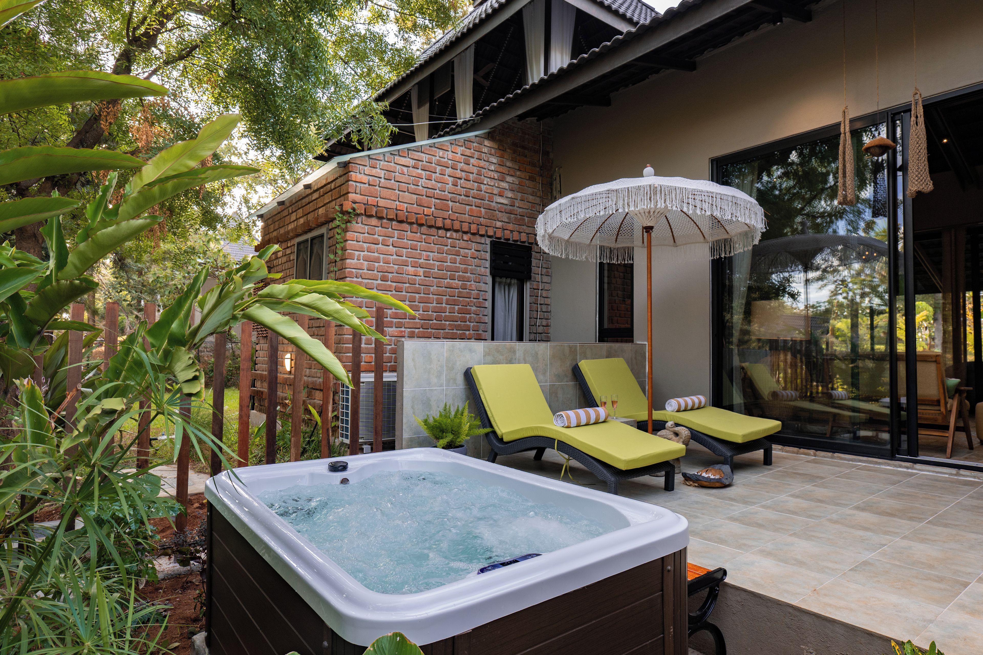 A spa area with a hot tub, lounge chairs, and a large umbrella.