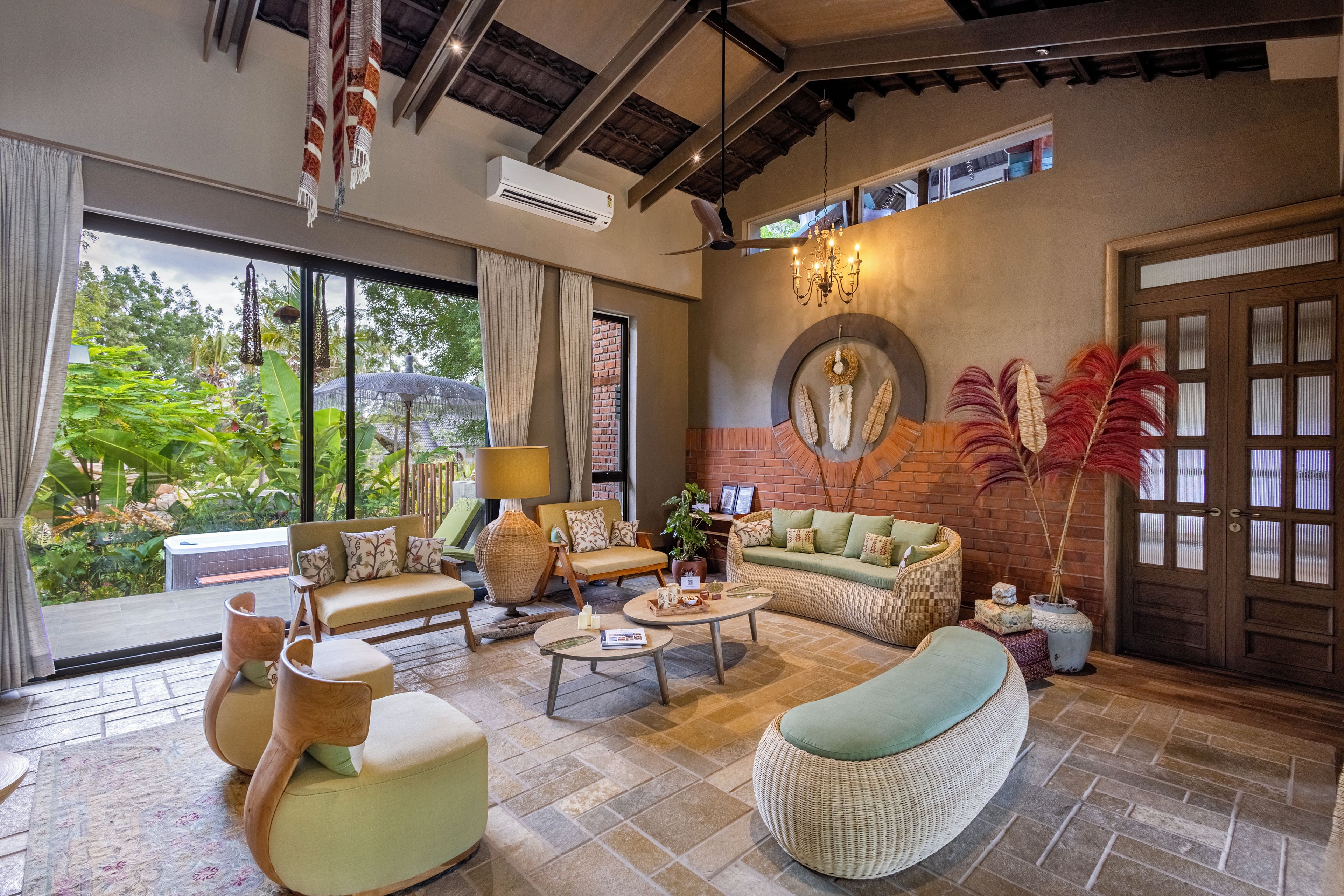 A spacious living area with a sofa, chairs, a coffee table, and a view of greenery through large windows.