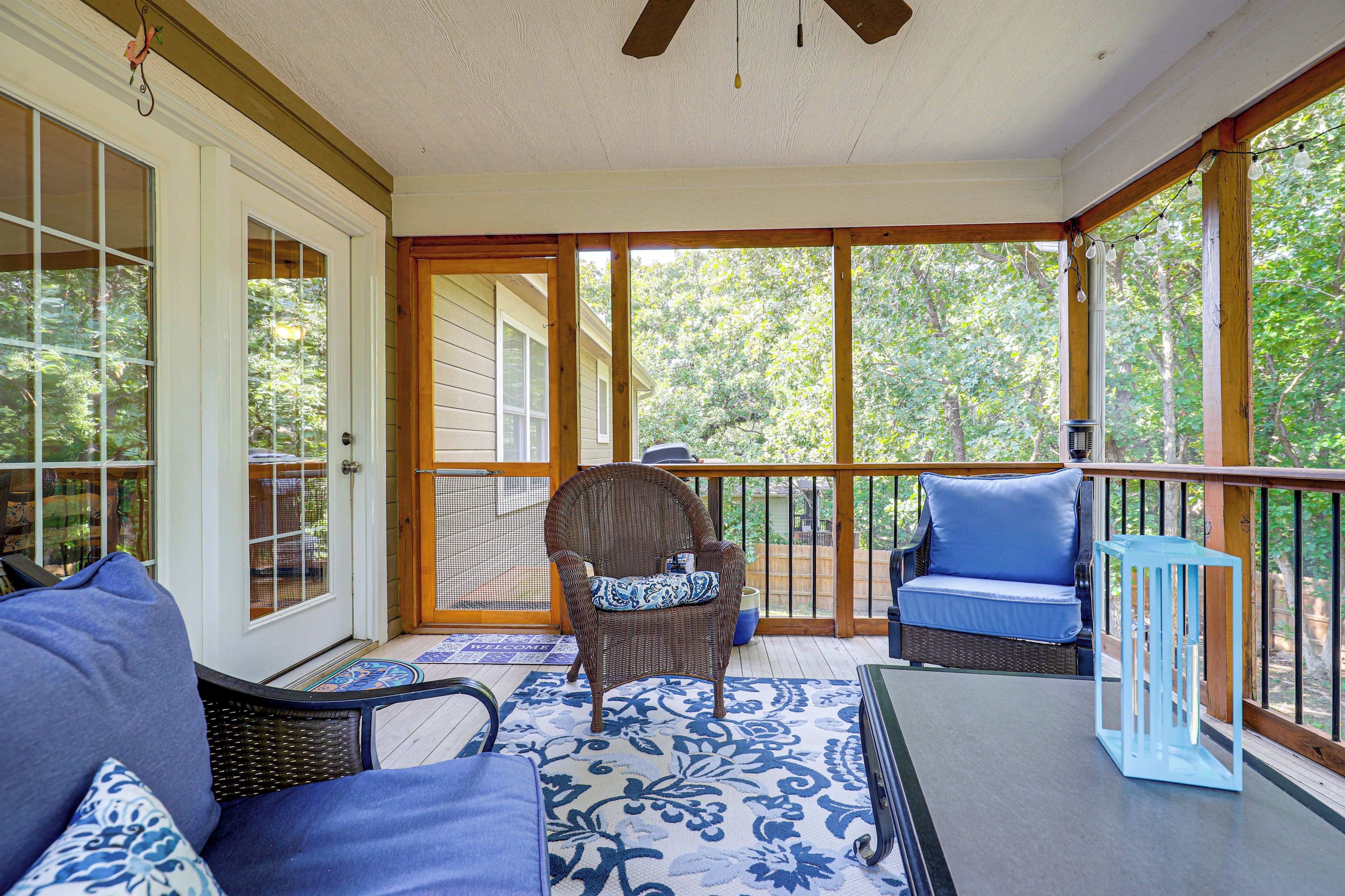 A covered porch with a seating area, including a chair and a sofa, and a table.