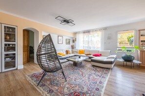 Un salon comprenant un canapé, une table basse, un tapis à motifs et un fauteuil original.