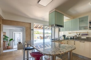Une cuisine moderne dotée d’un comptoir en granit, d’appareils électroménagers en acier inoxydable et offrant une vue sur l’extérieur.