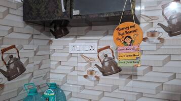 Eine Küche mit modernem Design, inklusive einer Wand mit Musterfliesen, hängenden Wasserkochern und einem an der Wand befestigten Schild mit Teesorten.