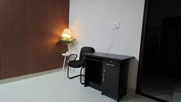 Een kleine kamer met een behang, een bureau met stoel, en een stopcontact.