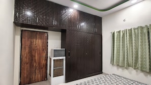 A room with a wardrobe, an air conditioner, a patterned floor, and a curtain.