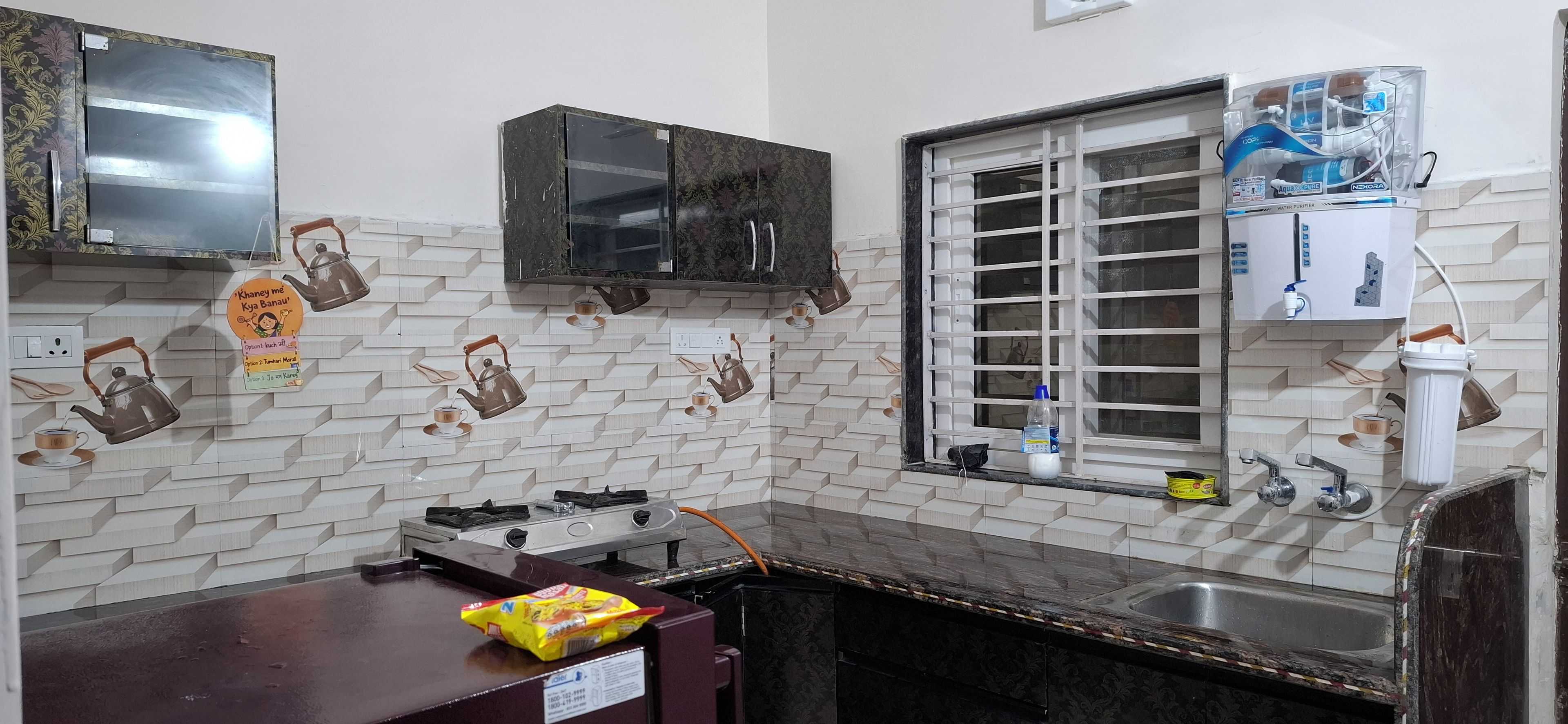 A kitchen with a tiled backsplash, a window with a water purifier, and a gas stove.