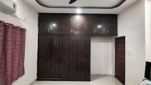 A room with a wardrobe, a ceiling fan, and a power outlet.