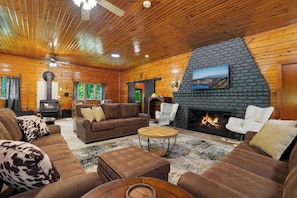 Ein gemütliches Blockhaus-Interieur mit Kamin, Ledersofas und einer Wand aus Naturstein.