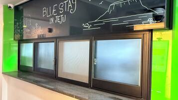 A reception desk with a sign that reads 'BLUE STAY IN JEJU' and a drawing of a ship.