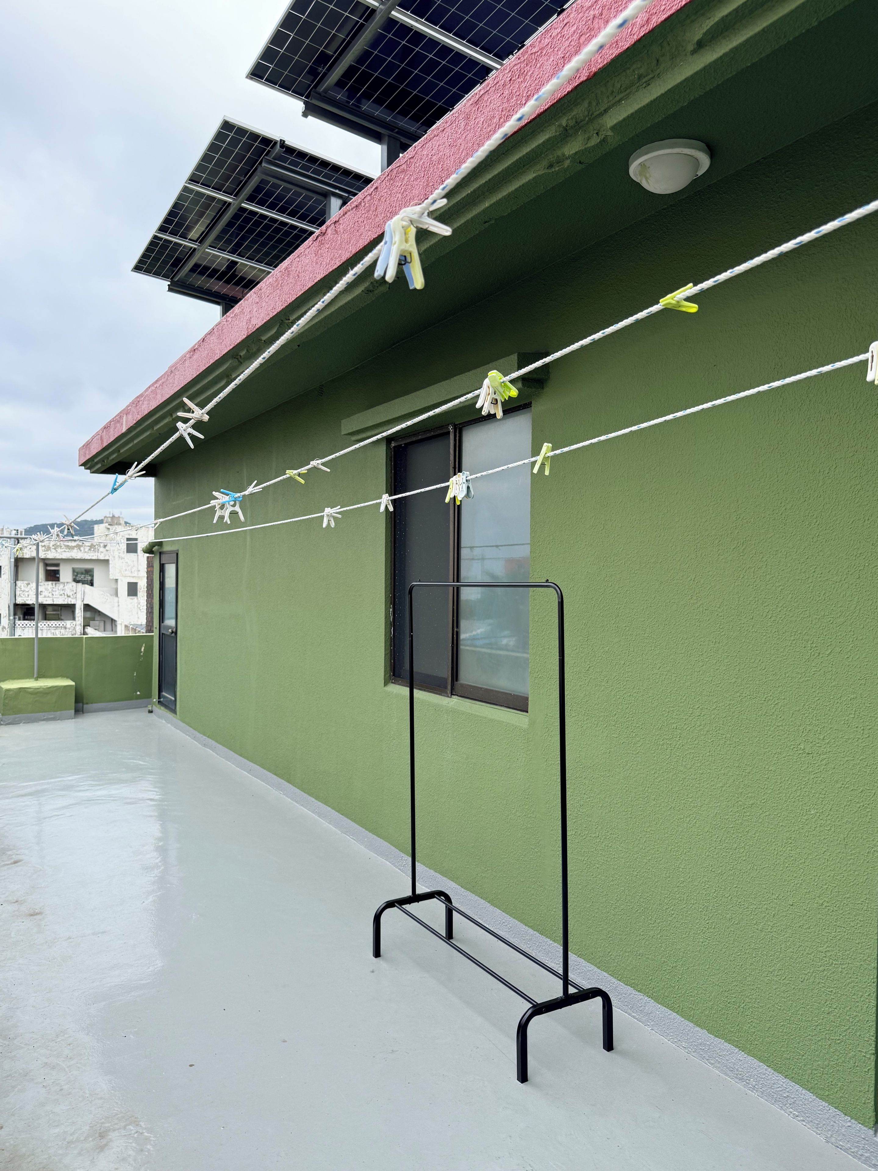 A rooftop with solar panels, a green wall, and a clothesline with clothes.