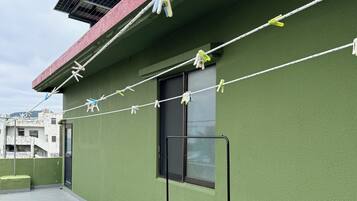 A rooftop with solar panels, a green wall, and a clothesline with clothes.