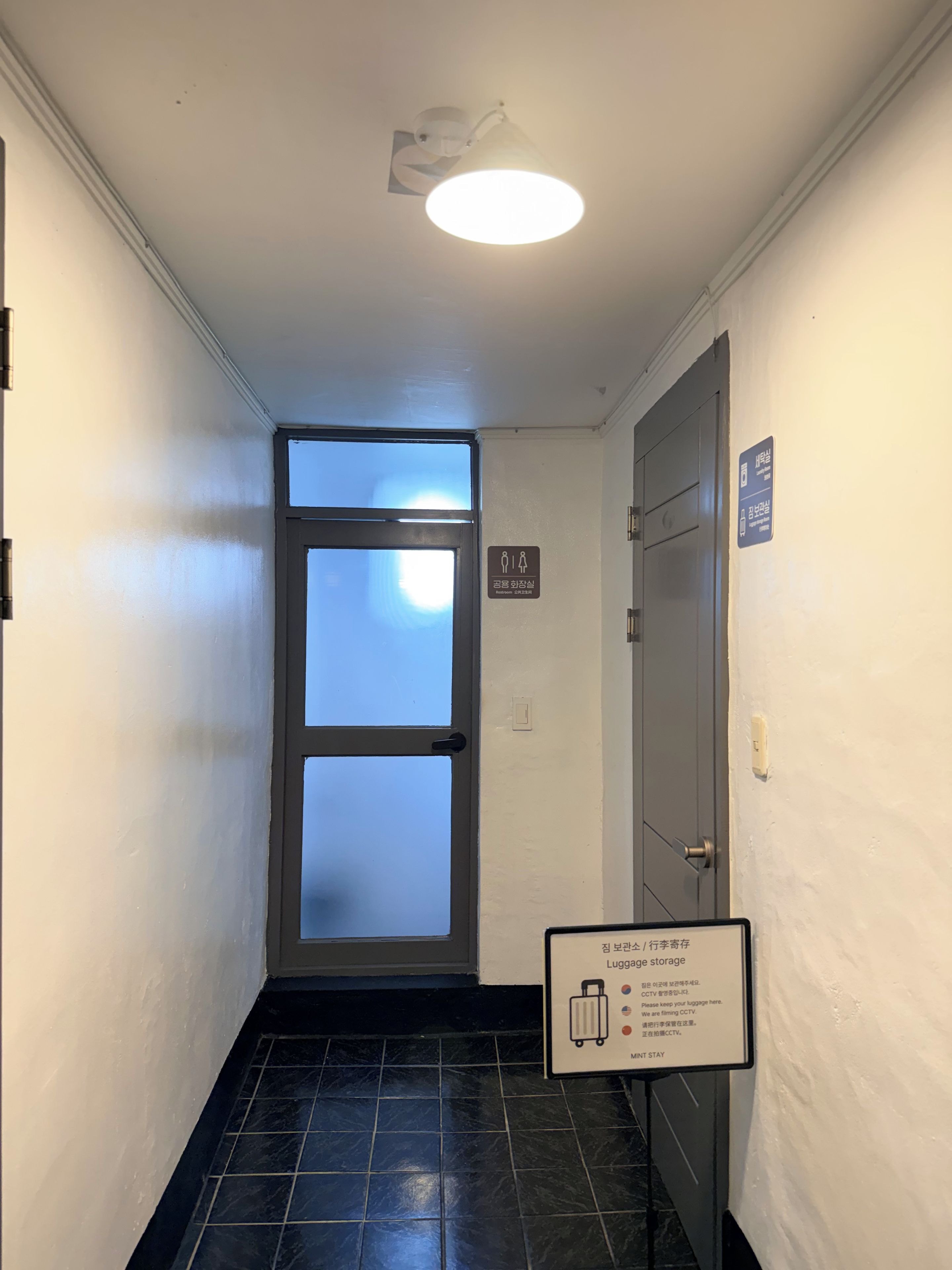 A hallway with a door, a sign indicating a women's restroom, and a luggage storage sign.