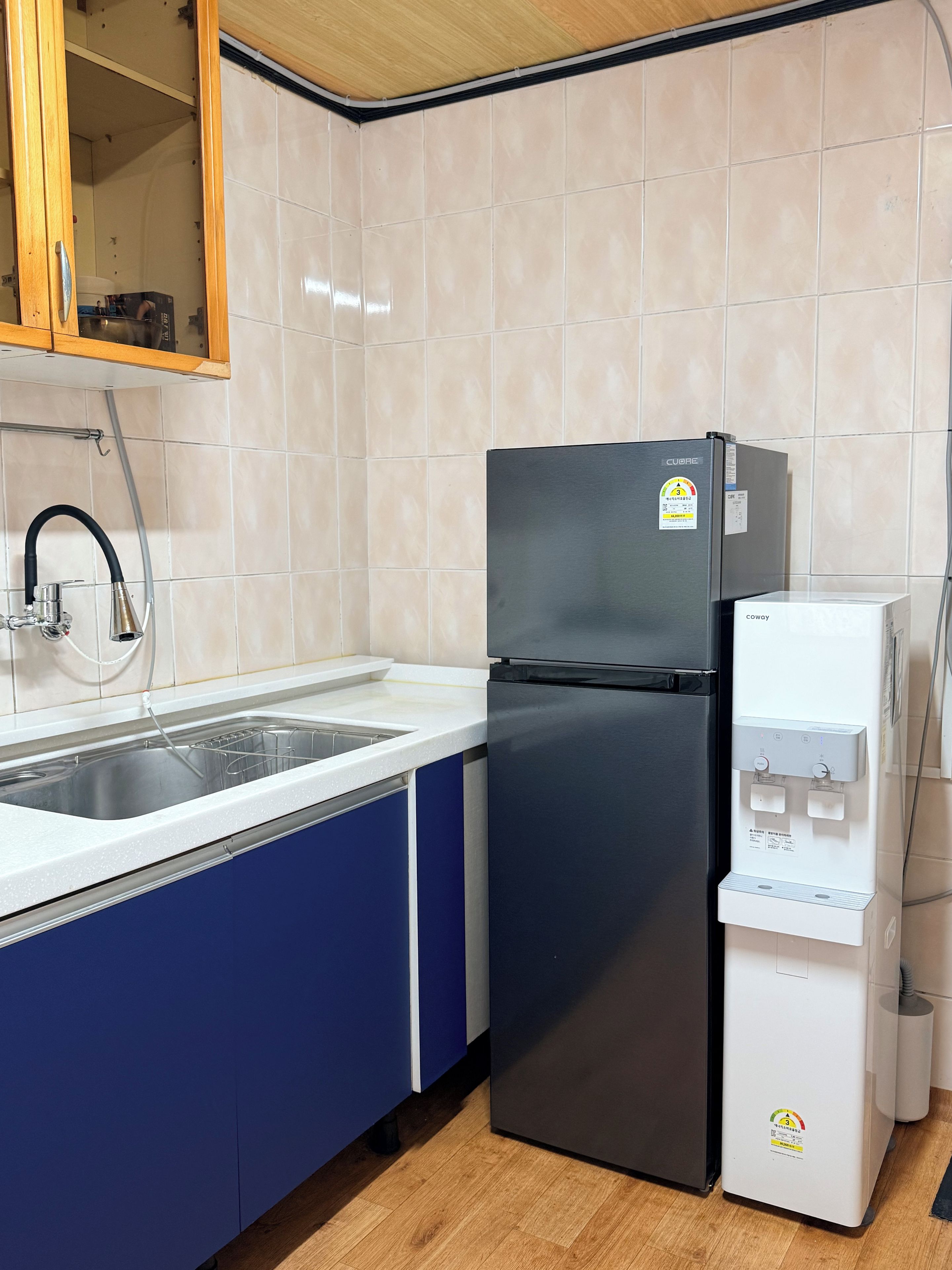 Una cocina con un refrigerador negro, un dispensador de agua y un lavabo con grifo.