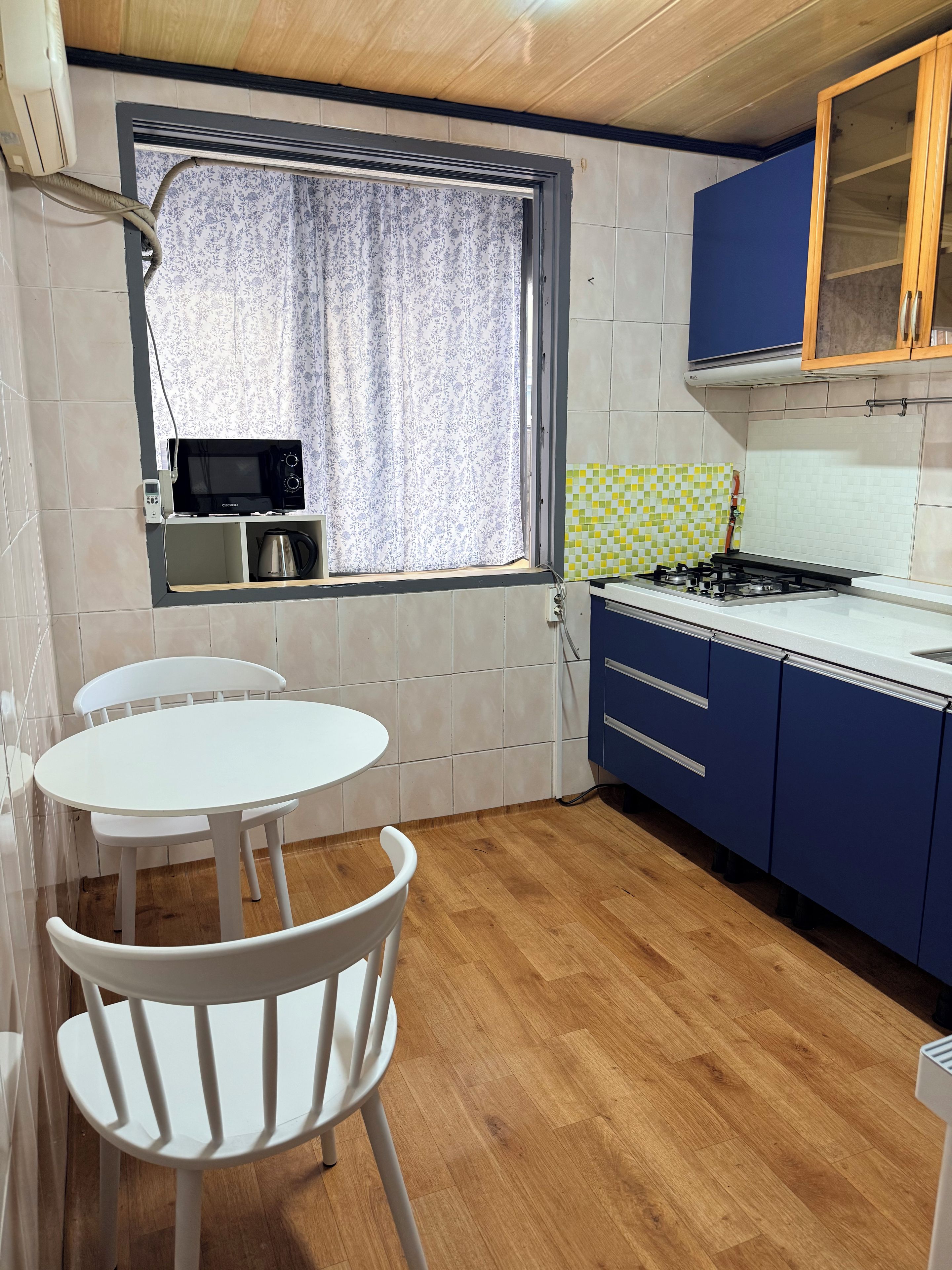 A kitchen with a gas stove, a microwave, and a small table with chairs.