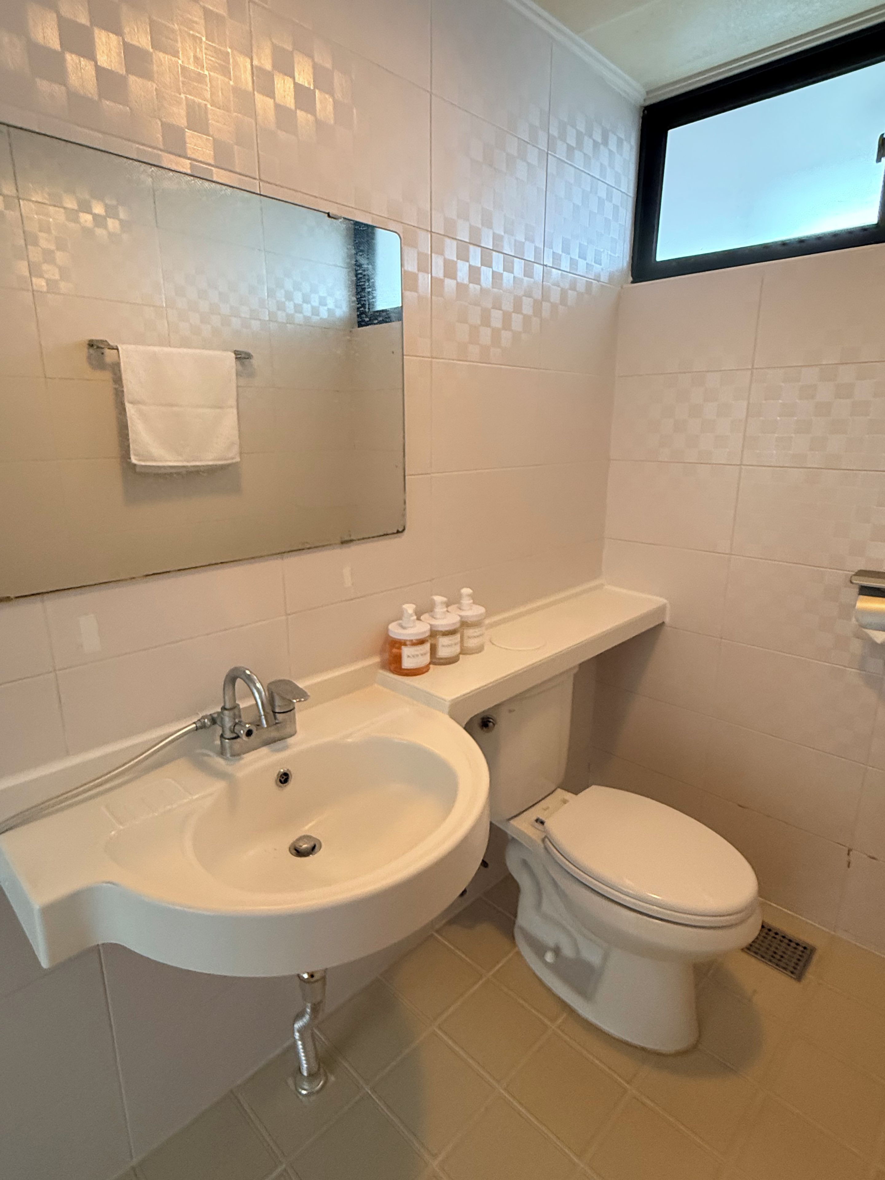 A bathroom with a white sink, mirror, and toilet.