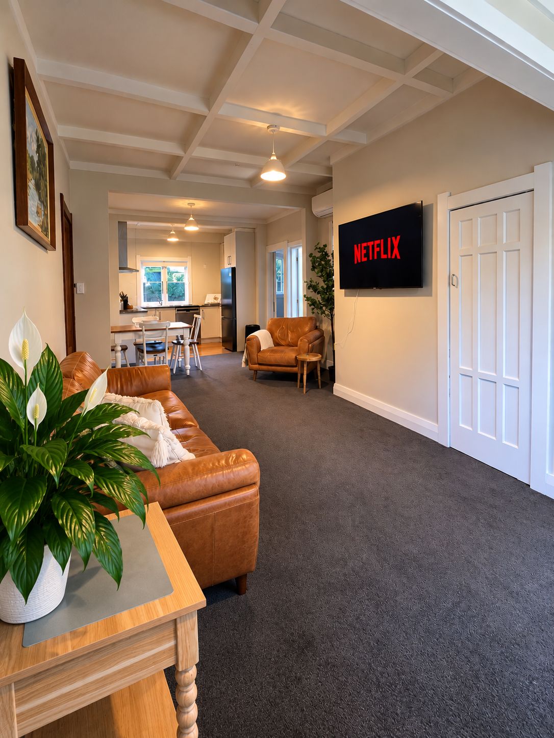 Spacious lounge with leather seating, smart TV, and open dining area