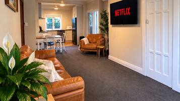 Spacious lounge with leather seating, smart TV, and open dining area