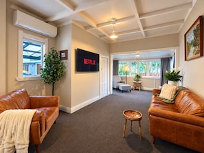 A living room with leather sofas, a TV mounted on the wall, and a ceiling fan.