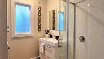 Bright modern bathroom with glass shower and warm wood-style floors