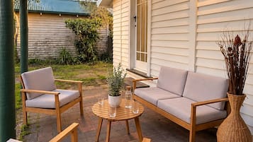 A covered patio area with a wooden bench, a sofa, and a table.