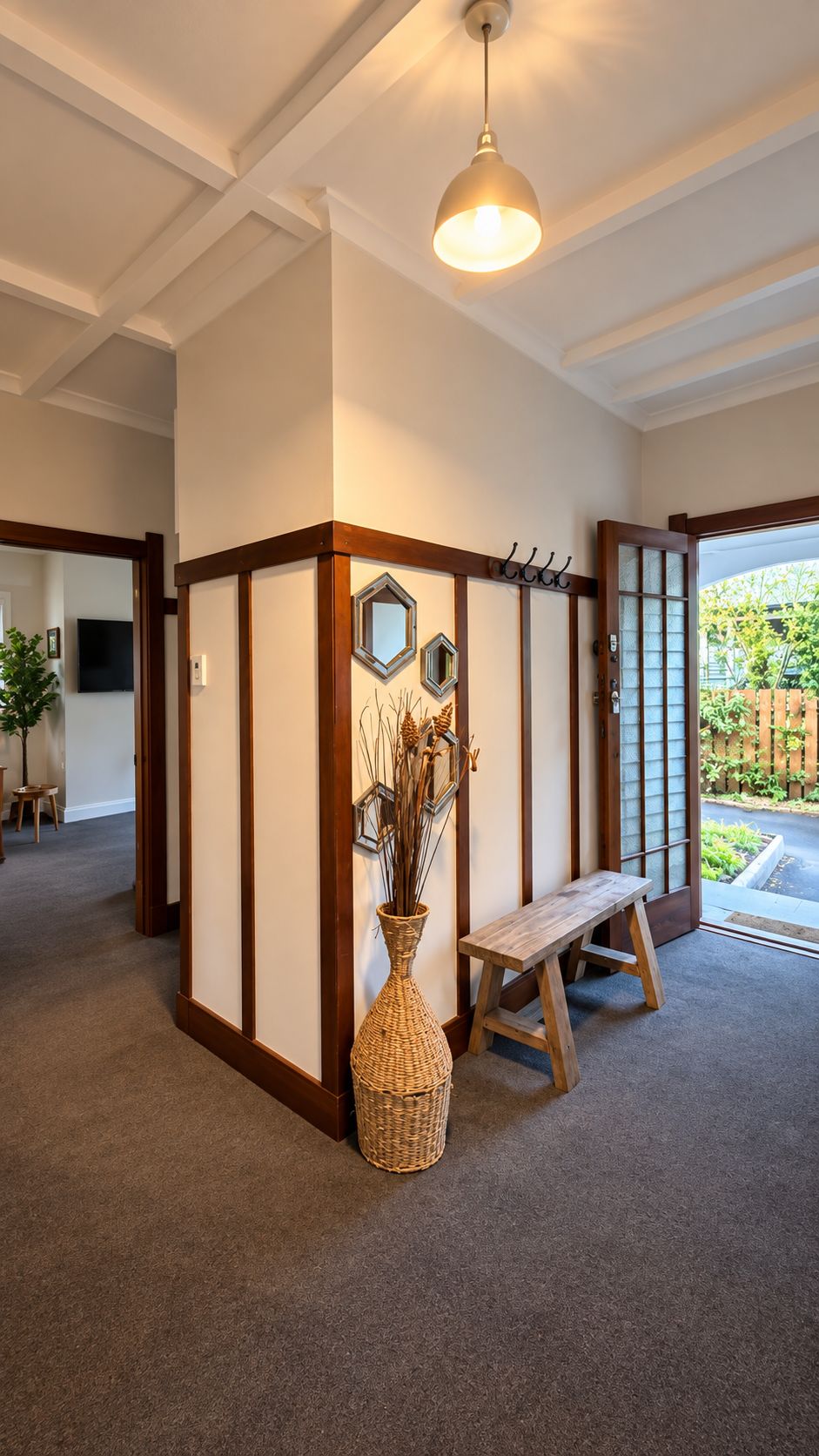 A room with a wooden bench, a woven basket, and a hanging light fixture.