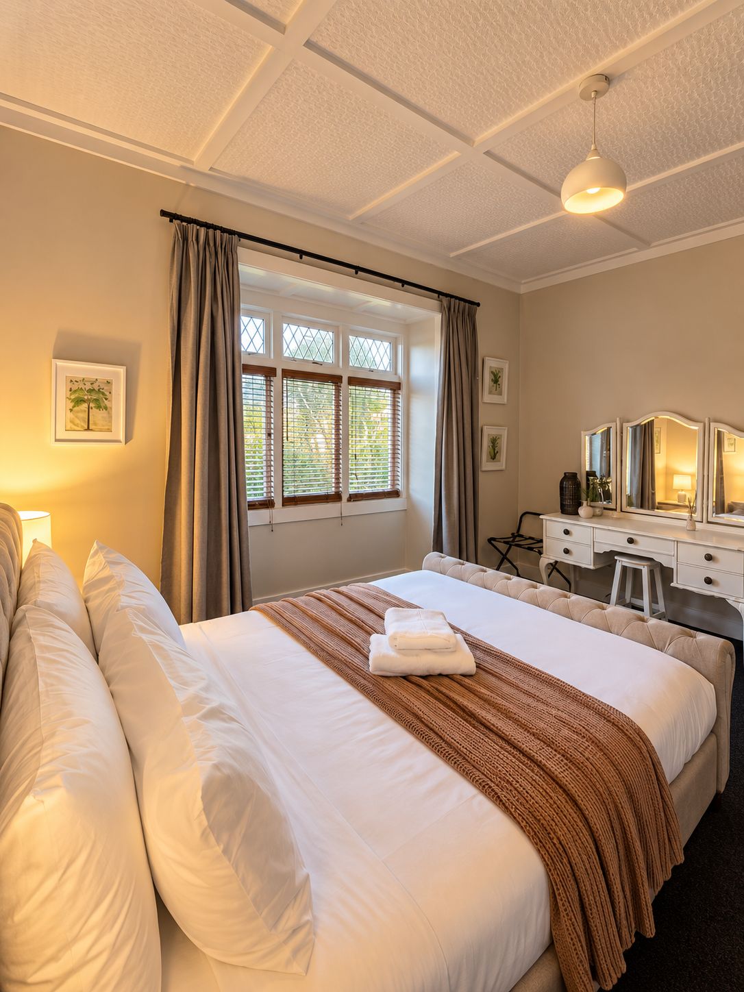 Habitación de hotel con una cama grande, un escritorio con espejo y una ventana con cortinas.