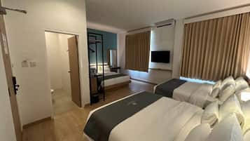 Habitación de hotel con dos camas, televisión, escritorio y ventana con cortinas.