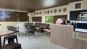 A modern kitchen with a bar area, seating, and a patterned floor. - Anamcara Hotel & Covention by Alltrue (Cipanas)