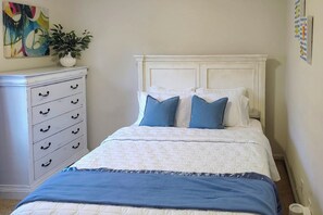Une chambre à coucher comprenant un lit, une commode et une étagère fixée au mur, sur laquelle est posée une plante.