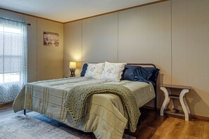 Ett sovrum med en säng, ett sängbord, en lampa och ett fönster med gardiner.