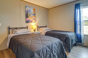 A room with two beds, a painting on the wall, a lamp on a bedside table, and a window with curtains. - Explore Oklahoma! Grand Lake - Rock Crawling (Jay)