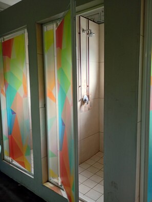 Ett badrum med dusch, kaklade väggar och färgglada, geometriska mönster på glasdörrarna.