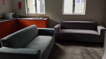 A room with two sofas, a microwave, and a window with a view.