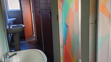A narrow hallway with a white sink and a window with colorful geometric patterns.