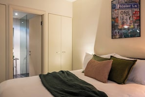 Ein Schlafzimmer mit einem Bett, Kissen, einer Decke, einem Kleiderschrank und einer Tür zu einem Badezimmer.