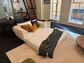 Ein Zimmer mit einem Bett, einem Schreibtisch, einem Stuhl, einer Treppe und einem Fenster.
