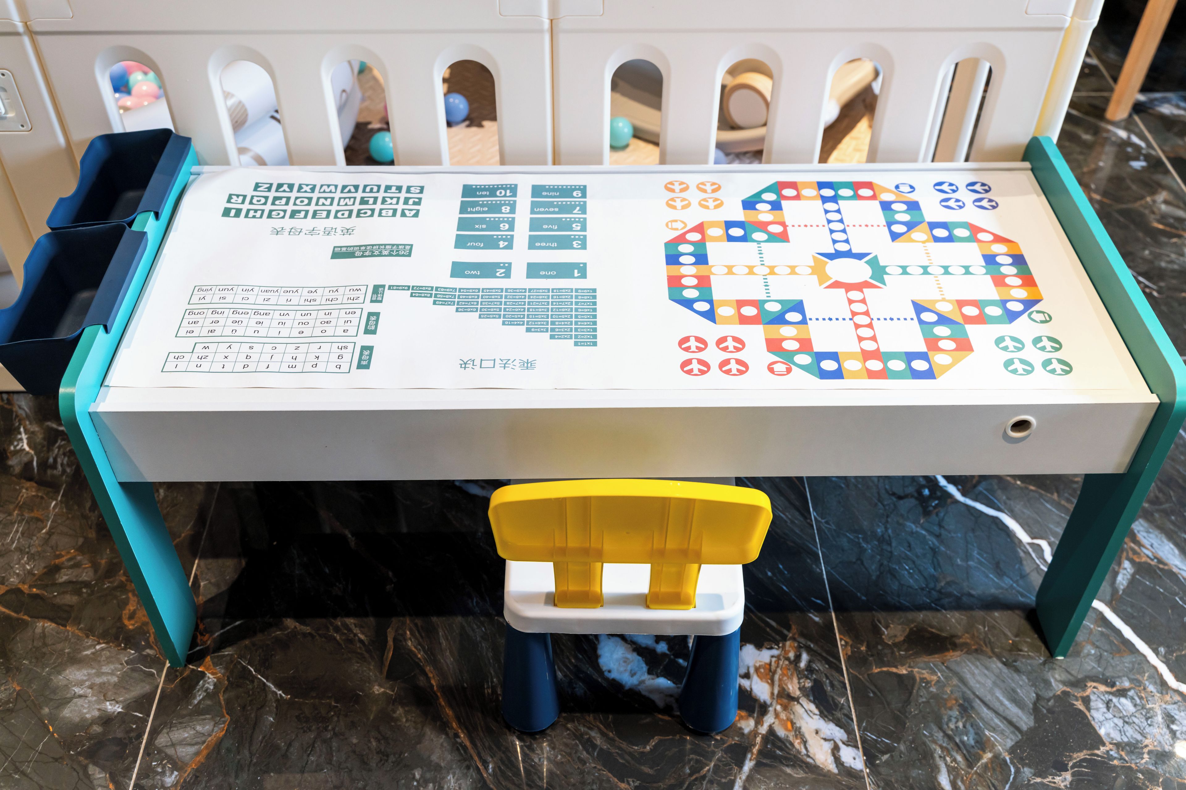 Una mesa para juegos de mesa con tablero, fichas y una silla amarilla.