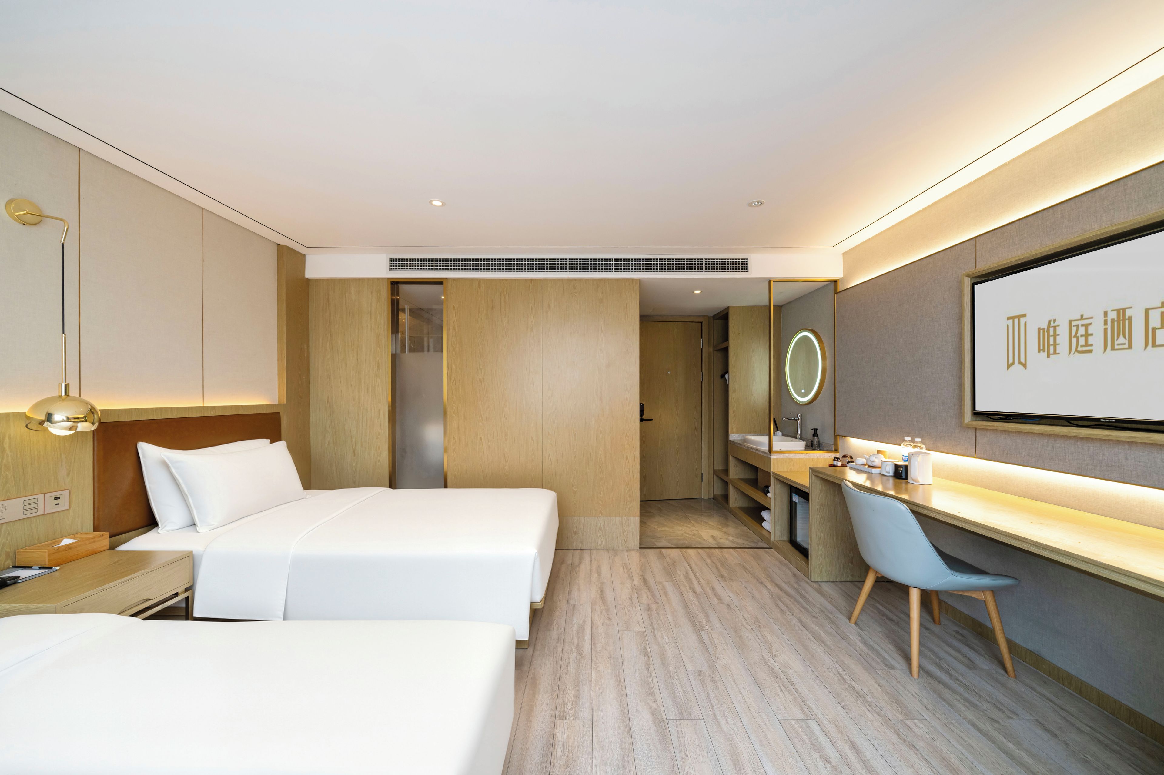 Habitación de hotel con dos camas, un escritorio, una silla, un espejo y un ventanal grande.
