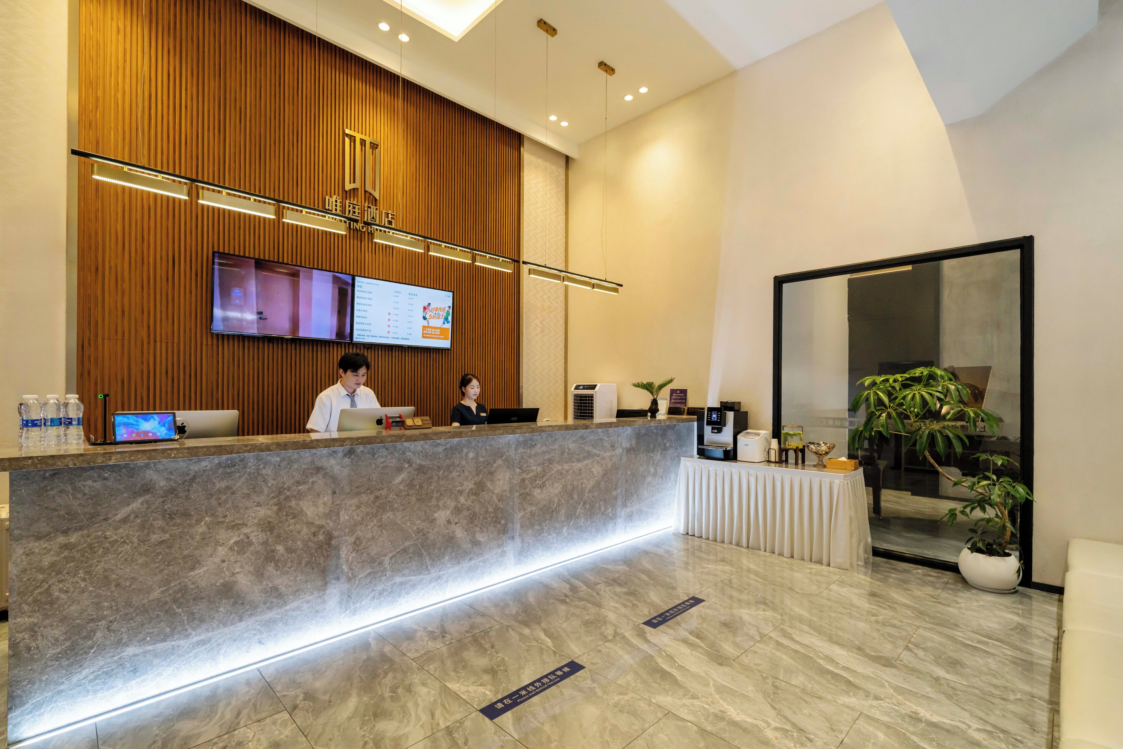 A hotel reception area with a marble counter, a flat-screen TV, and a reception desk.
