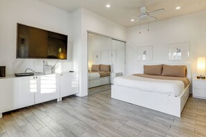 Quarto moderno com cama, mesas de cabeceira, televisão e guarda-roupa.