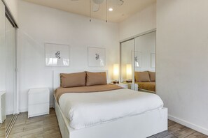 A bedroom with a bed, bedside tables, a mirror, and framed artwork on the wall. - Boardwalk Escape: Beachfront Santa Monica Condo (Santa Monica)