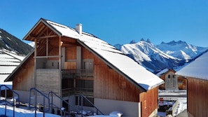 A wooden chalet with a balcony, set against a backdrop of snow-covered mountains. - Sybelles Ski Area | Sleeps 6 | Ski-in Paradise (Saint Sorlin d'Arves)