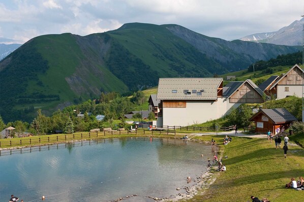 Vista de un lago con una casa de madera y una pequeña construcción de madera cerca del agua.