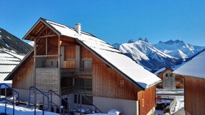 A wooden chalet with a balcony, set against a backdrop of snow-covered mountains. - Sybelles Ski Area | Sleeps 8 | Ski-in Paradise (Saint Sorlin d'Arves)