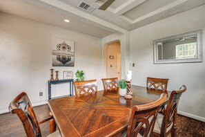 Une salle à manger avec une table et des chaises en bois, un tableau au mur et un miroir.