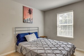 Une chambre à coucher avec un lit, une fenêtre avec des stores et un tableau accroché au mur.